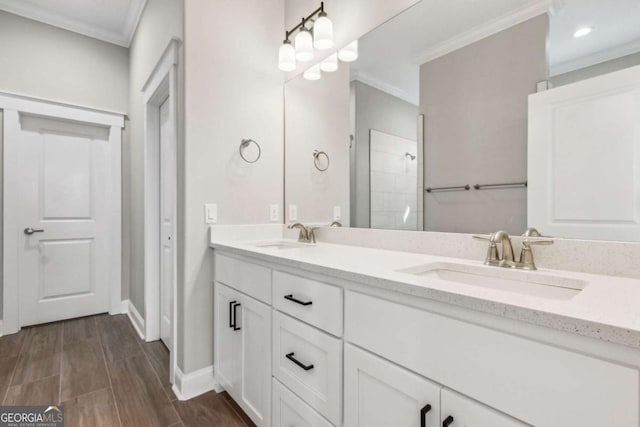 bathroom with a tile shower, double vanity, ornamental molding, and a sink