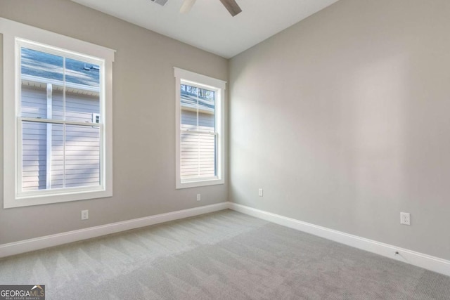 empty room with a healthy amount of sunlight, light carpet, ceiling fan, and baseboards