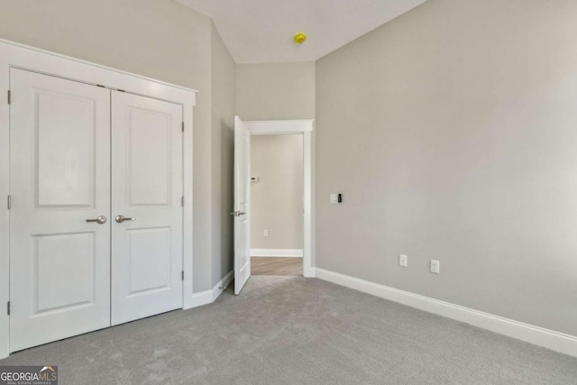 unfurnished bedroom featuring a closet, light carpet, and baseboards