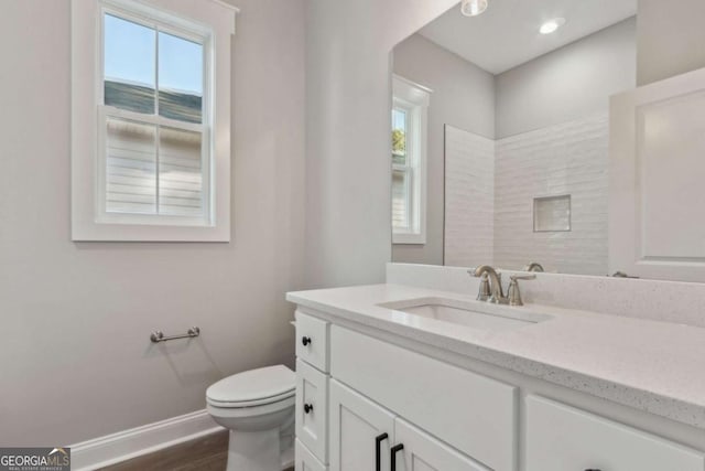 bathroom with toilet, baseboards, wood finished floors, and vanity