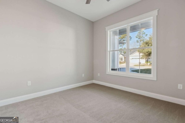 carpeted spare room featuring a ceiling fan and baseboards