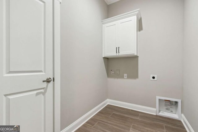 washroom with cabinet space, hookup for an electric dryer, dark wood finished floors, and baseboards