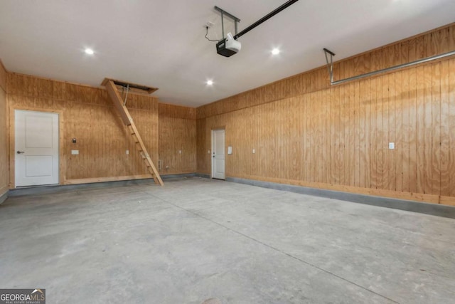 garage with a garage door opener and wood walls