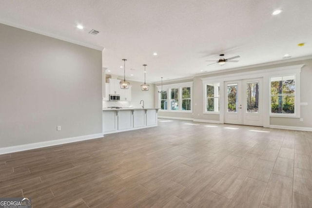 unfurnished living room with wood finish floors, visible vents, and baseboards