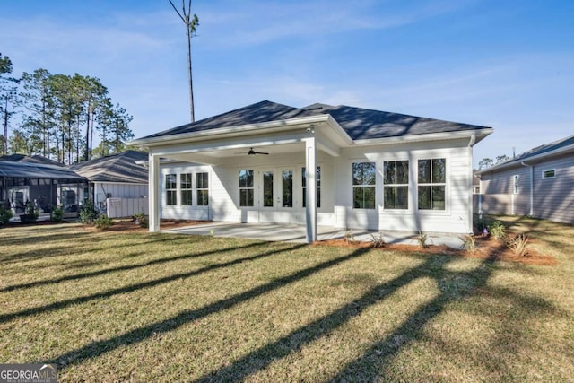 rear view of property featuring a ceiling fan, roof with shingles, a patio, and a lawn