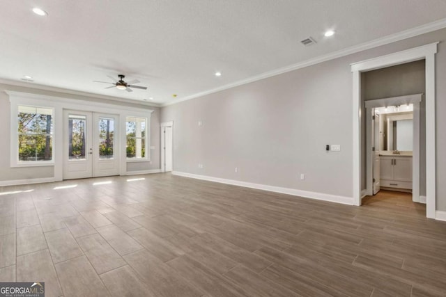 unfurnished living room with baseboards, visible vents, crown molding, and wood finish floors