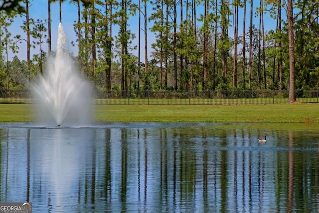 property view of water with fence and a wooded view