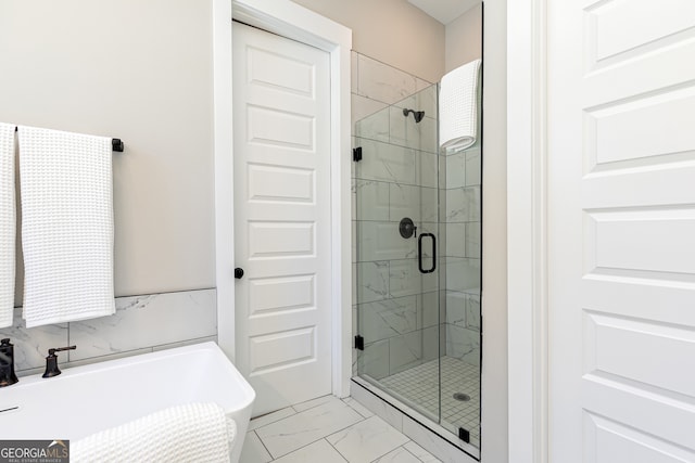 bathroom with a sink, marble finish floor, a freestanding bath, and a stall shower