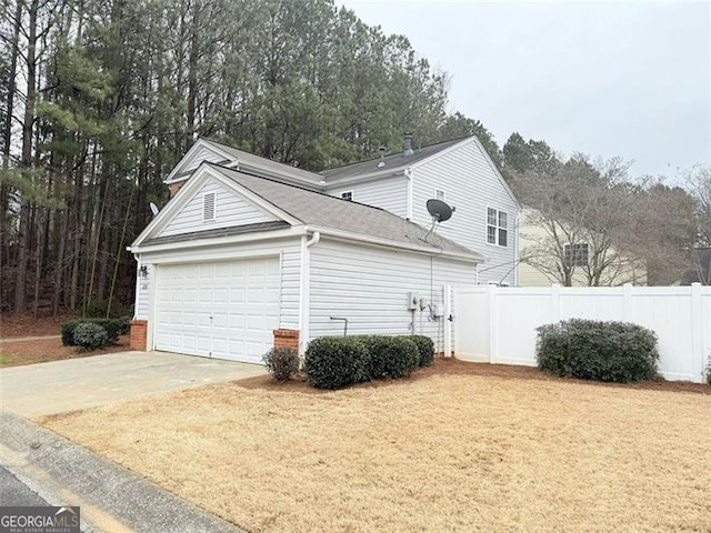 view of side of property featuring a garage, fence, and concrete driveway