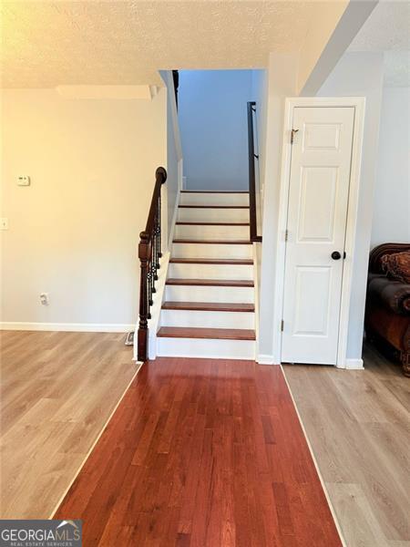 stairway featuring a textured ceiling, baseboards, and wood finished floors