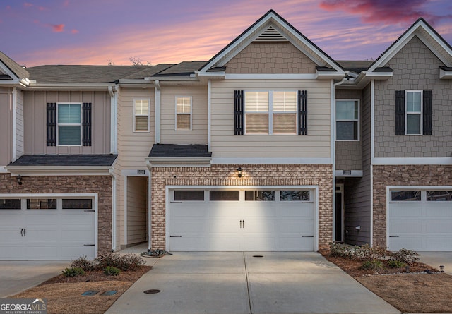 view of property featuring a garage, brick siding, and driveway