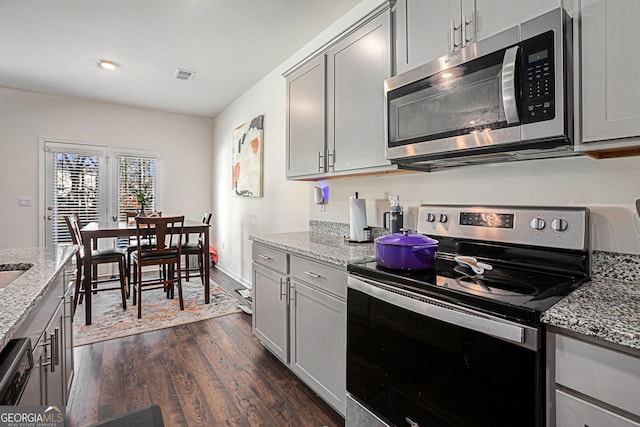 kitchen with visible vents, dark wood-style floors, appliances with stainless steel finishes, light stone counters, and gray cabinets