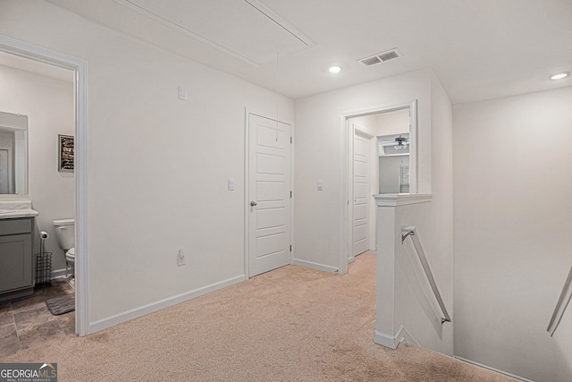 hall with light colored carpet, visible vents, attic access, an upstairs landing, and baseboards