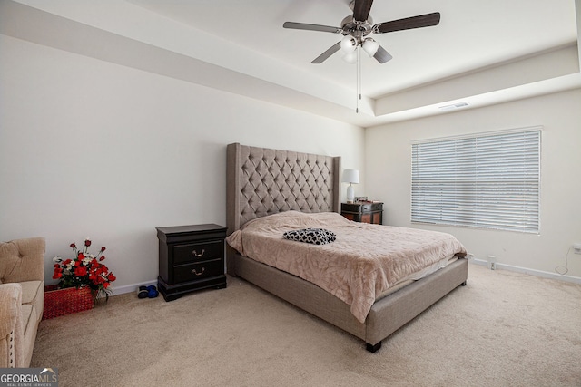 carpeted bedroom featuring a tray ceiling, visible vents, ceiling fan, and baseboards