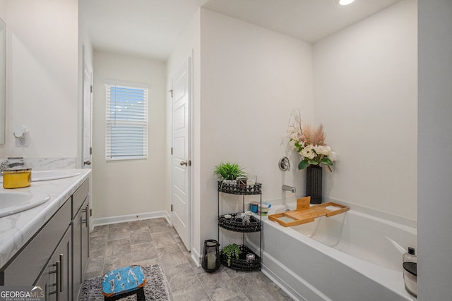 bathroom with double vanity, baseboards, a washtub, and a sink