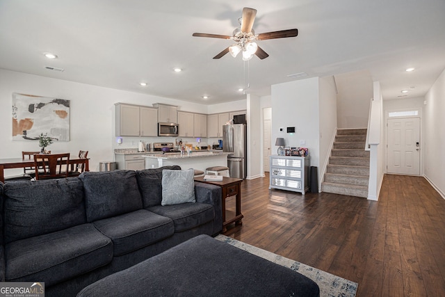 living area with recessed lighting, visible vents, dark wood finished floors, and stairs