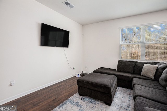 living room with light wood-type flooring, visible vents, and baseboards