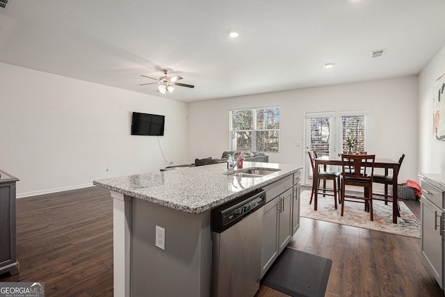 kitchen featuring gray cabinetry, dark wood-type flooring, a sink, stainless steel dishwasher, and a center island with sink