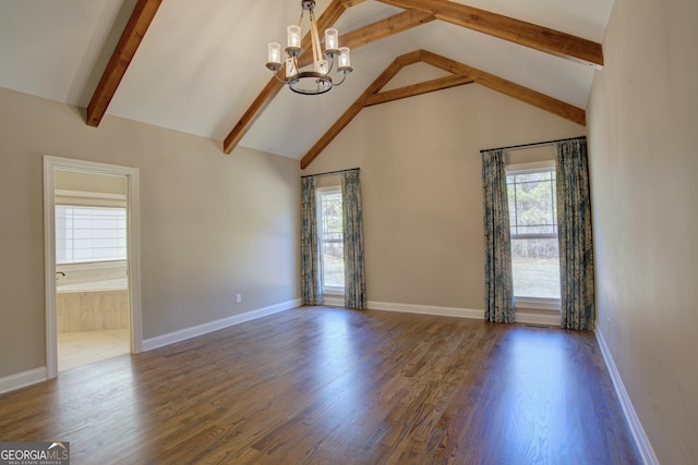 spare room with a chandelier, a healthy amount of sunlight, dark wood finished floors, and beamed ceiling