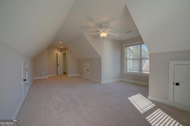 additional living space with baseboards, visible vents, vaulted ceiling, and light colored carpet