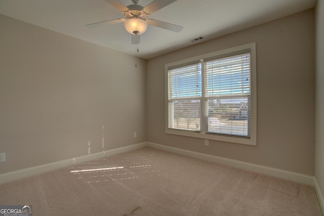 unfurnished room featuring light carpet, ceiling fan, visible vents, and baseboards