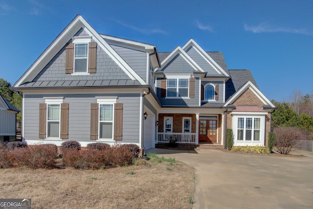 craftsman-style home with metal roof, a porch, brick siding, concrete driveway, and a standing seam roof