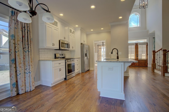 kitchen featuring appliances with stainless steel finishes, white cabinetry, glass insert cabinets, and a sink