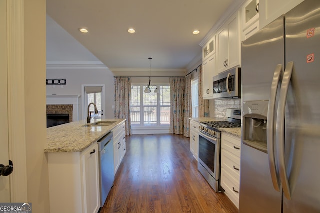 kitchen featuring pendant lighting, stainless steel appliances, glass insert cabinets, white cabinetry, and a sink