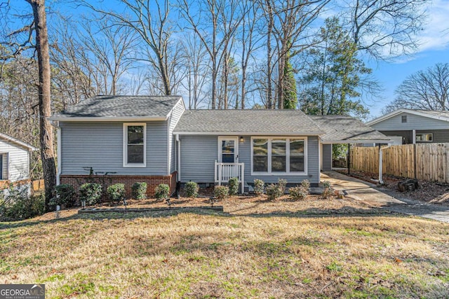 view of front of house with brick siding, fence, an attached carport, and a front yard