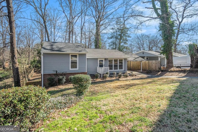 rear view of property with a lawn and fence