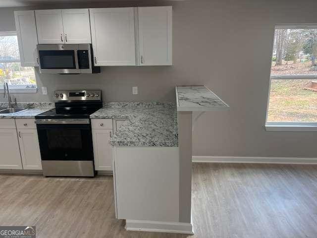 kitchen featuring stainless steel appliances, a healthy amount of sunlight, and white cabinets