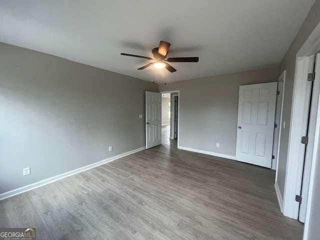 unfurnished bedroom featuring ceiling fan, dark wood finished floors, and baseboards