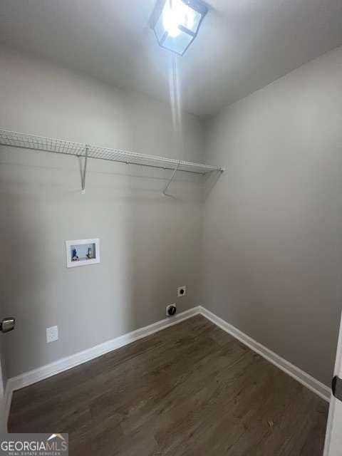 clothes washing area featuring dark wood finished floors, hookup for a washing machine, hookup for an electric dryer, laundry area, and baseboards