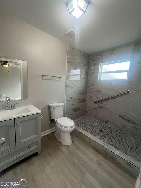 full bath with baseboards, toilet, wood finished floors, vanity, and a shower stall