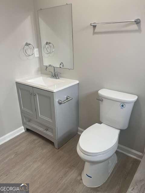 bathroom featuring toilet, wood finished floors, vanity, and baseboards