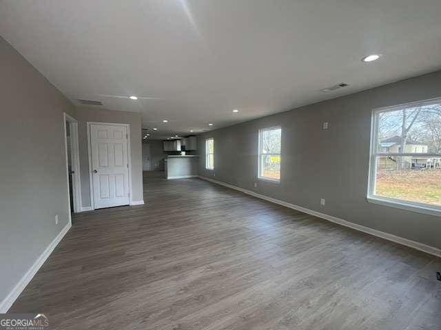 unfurnished living room with a healthy amount of sunlight, dark wood-style flooring, and baseboards