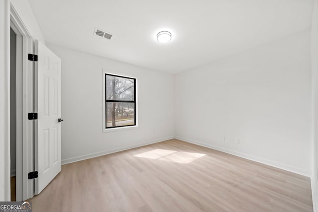 empty room featuring baseboards, visible vents, and light wood finished floors