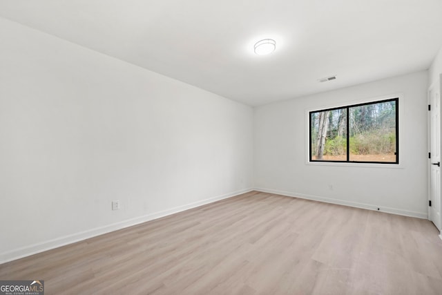 spare room featuring light wood-style floors, visible vents, and baseboards