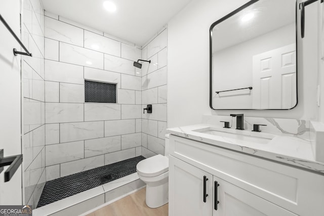 bathroom featuring wood finished floors, a stall shower, vanity, and toilet