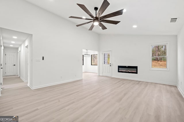 unfurnished living room featuring ceiling fan, light wood-style flooring, visible vents, baseboards, and a glass covered fireplace