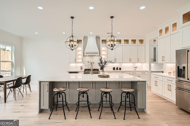 kitchen featuring decorative light fixtures, stainless steel appliances, light countertops, glass insert cabinets, and white cabinets