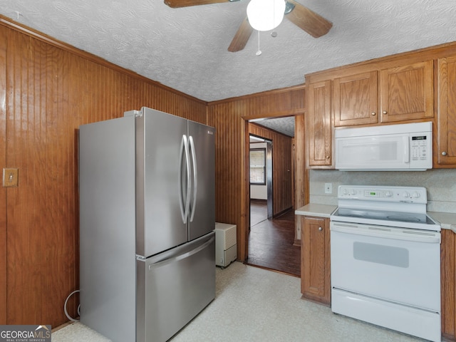 1713 Bramlett Shoals Rd, Lawrenceville, GA 30045 - kitchen featuring white appliances, brown cabinets, light countertops, wood walls, and ceiling fan