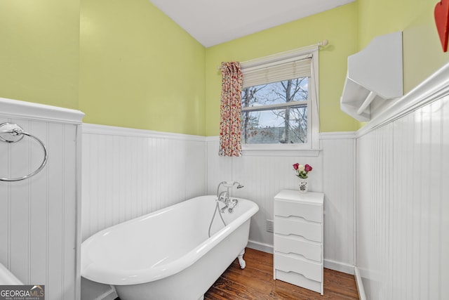 full bath featuring wainscoting, a soaking tub, and wood finished floors