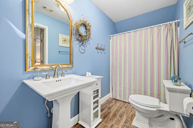 bathroom featuring baseboards, visible vents, toilet, and wood finished floors