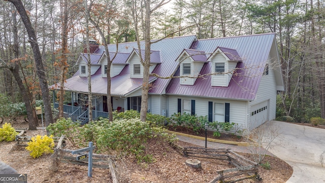 view of front of property featuring concrete driveway, metal roof, a chimney, and an attached garage