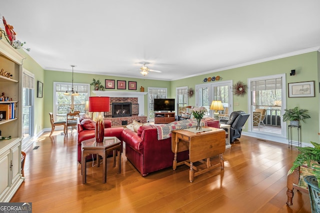 living area with ornamental molding, light wood-type flooring, a wealth of natural light, and baseboards