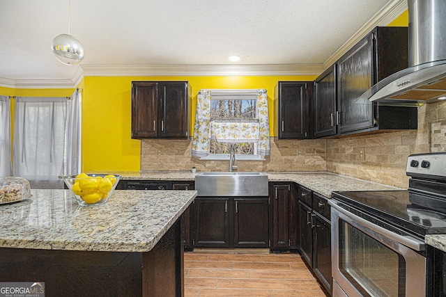 kitchen with wall chimney exhaust hood, hanging light fixtures, light stone countertops, stainless steel range with electric cooktop, and a sink