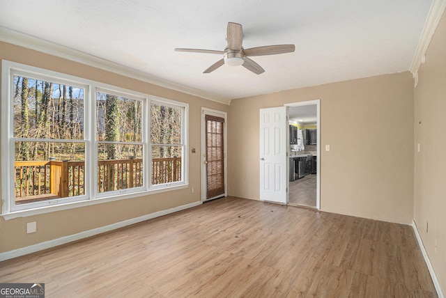 unfurnished room featuring a ceiling fan, light wood-type flooring, crown molding, and baseboards