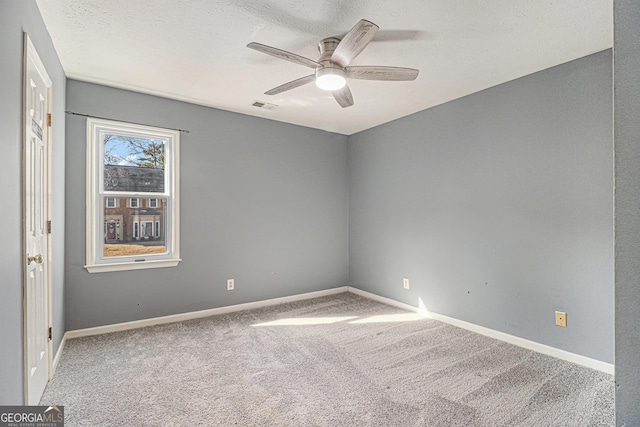 carpeted spare room with ceiling fan, a textured ceiling, visible vents, and baseboards