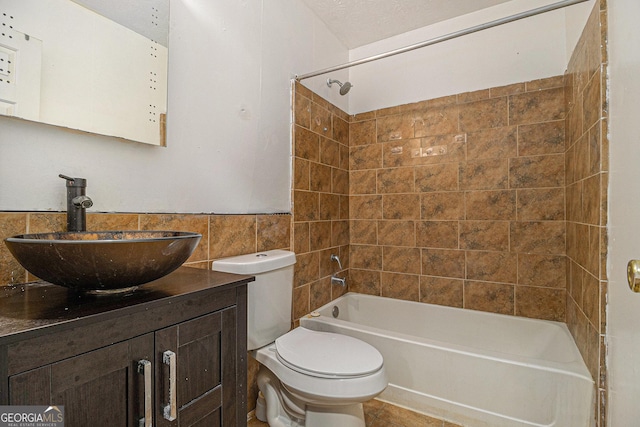 bathroom with tile walls, toilet, vanity, shower / tub combination, and tile patterned flooring